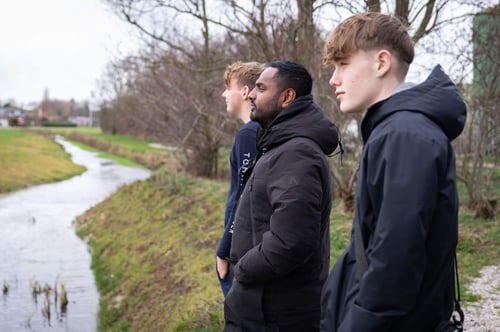 Coach-met-twee-jongeren-starend-over-het-water